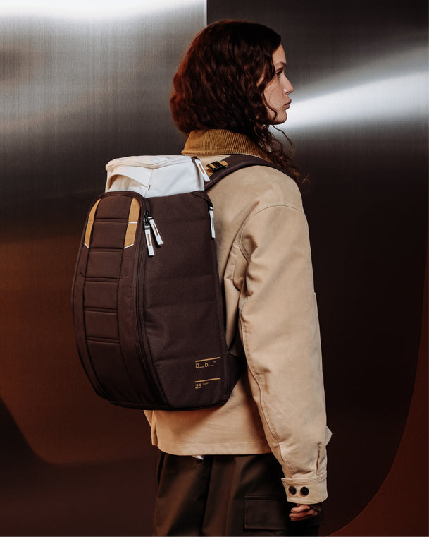 Woman wearing the Db Hugger Backpack 25L in Cappuccino brown and off-white.