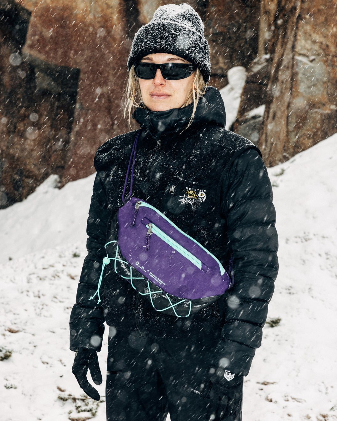 Db Roamer Pro 6L sling bag in purple worn across the chest in a snowy outdoor winter setting.