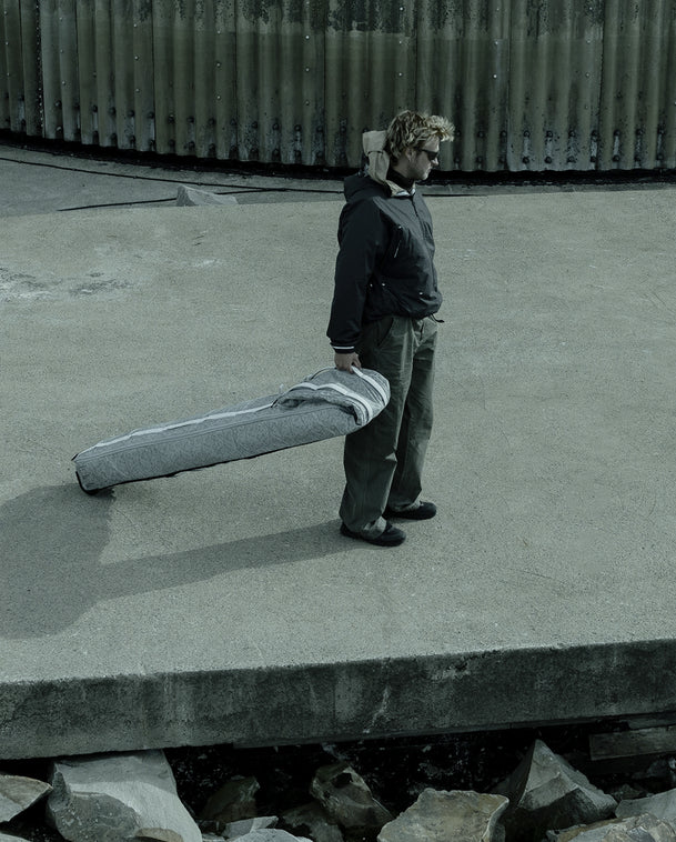 Man pulling the Snow Roller Pro 70L ski bag in White Noise across a concrete dock.